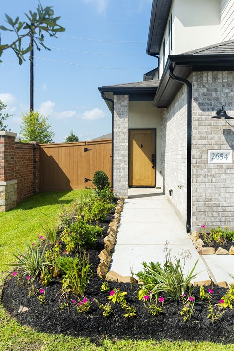 the front yard of a house with a walkway and flower garden