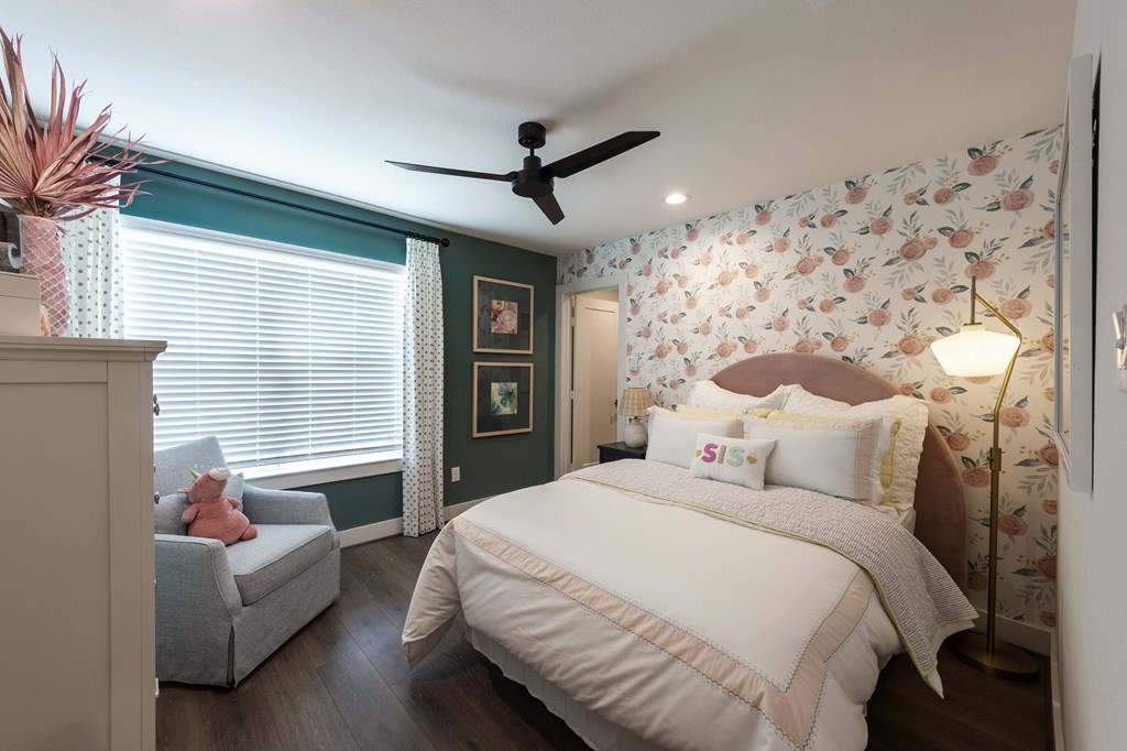 a bedroom with a bed and a chair and a ceiling fan