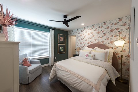 a bedroom with a bed and a chair and a ceiling fan