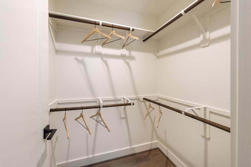 a spacious closet with white walls and a row of hangers