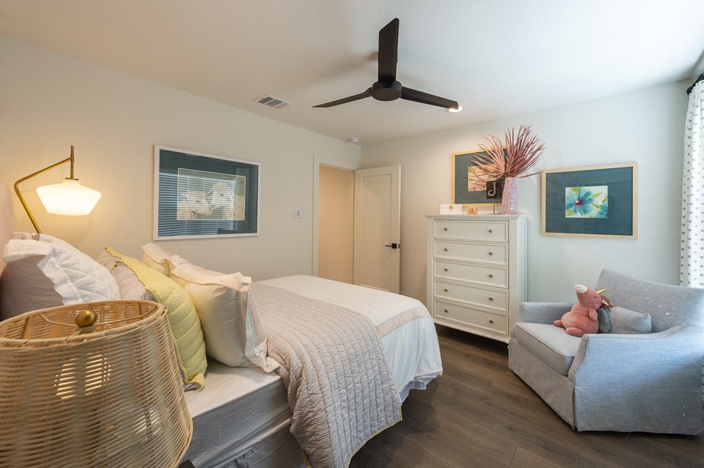 a bedroom with a bed and a chair and a ceiling fan