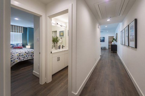 a long hallway with a bed and a mirror in a house
