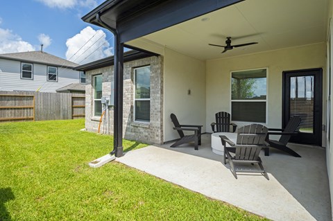 a covered patio with chairs and a ceiling fan