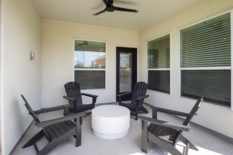 a porch with wooden rocking chairs and a round table