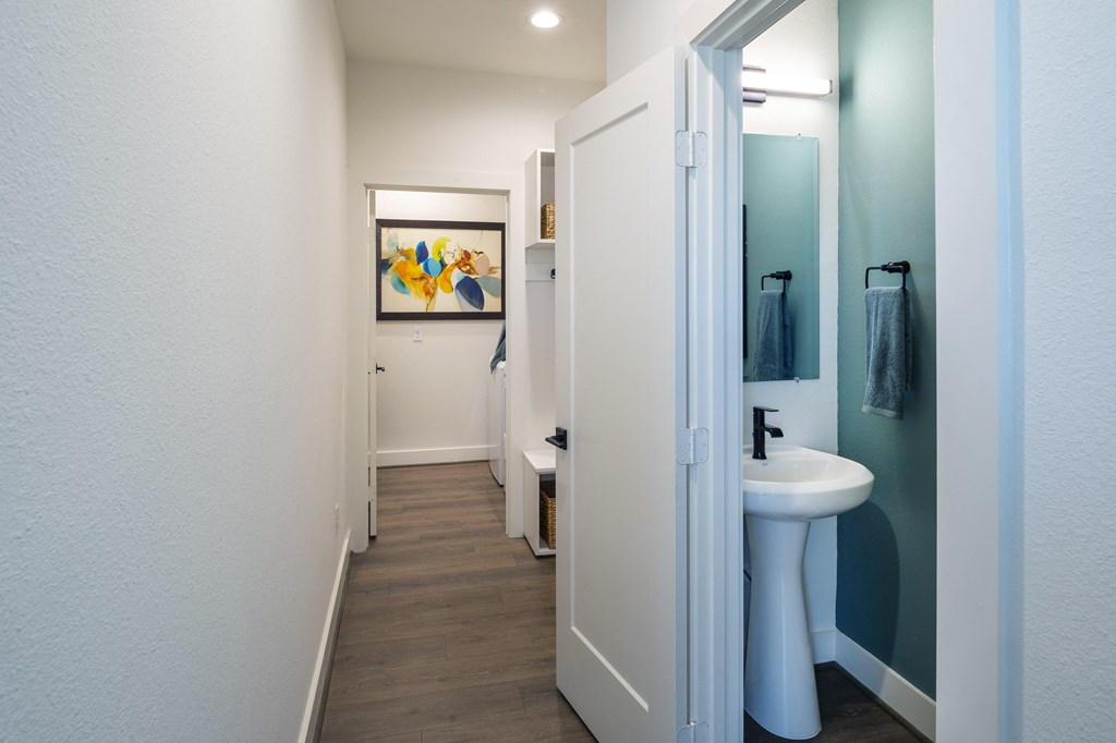 a bathroom with a sink and a mirror and a hallway with a door to a