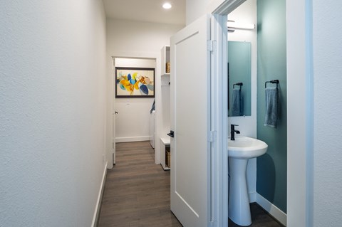 a bathroom with a sink and a mirror and a hallway with a door to a