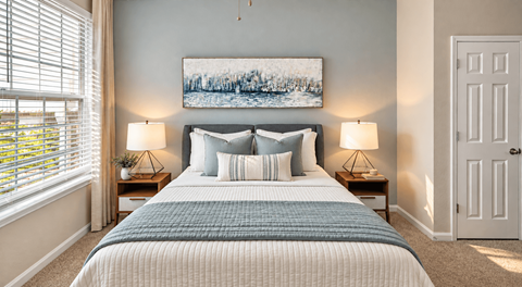 A bedroom with a large bed and a painting on the wall.