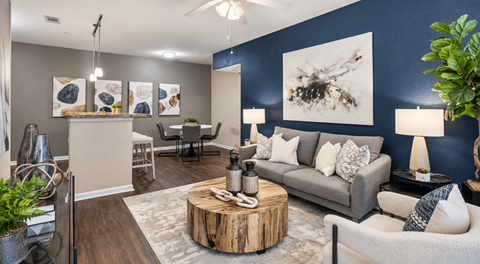 A living room with a grey couch, a wooden coffee table, and a painting of a bee on the wall.