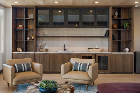 Two tan chairs with striped pillows sit in front of a kitchen island.
