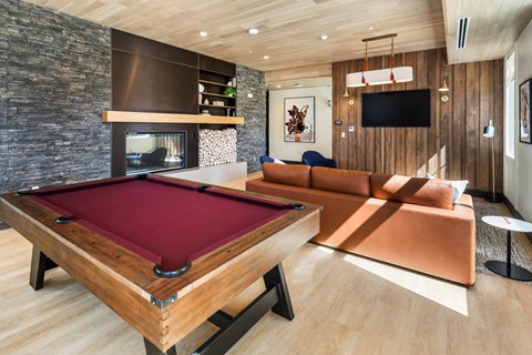 A pool table is in the middle of a room with a couch and a television.