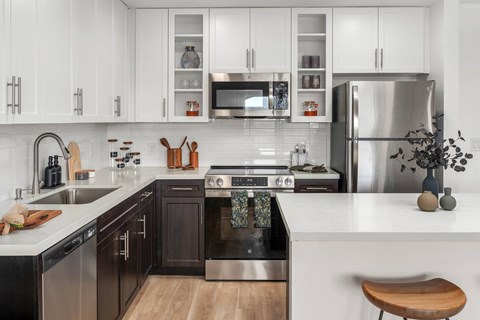 A modern kitchen with dark brown cabinets and stainless steel appliances.