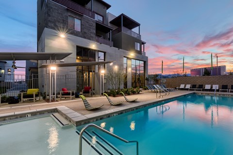 a swimming pool with lounge chairs and a building in the background