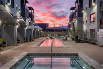 a sunset over an apartment complex with a pool in the foreground