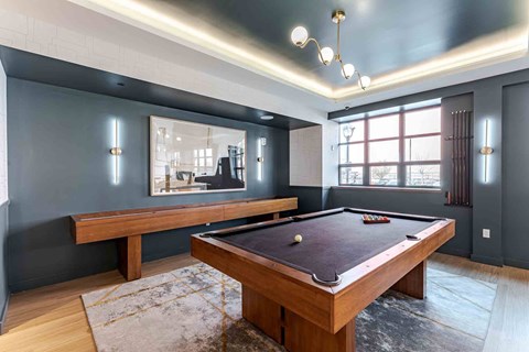 A pool table is in the middle of a room with a bench and a mirror.