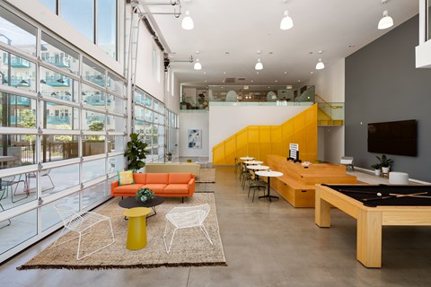 A brightly colored living room with a pool table and a balcony.