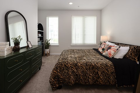 A bedroom with a leopard print bedspread and a green dresser.