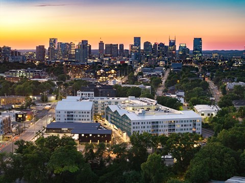 A cityscape at dusk with buildings illuminated and a clear view of the skyline.