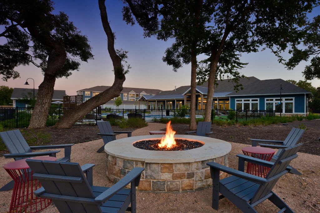 a fire pit with chairs in front of a house