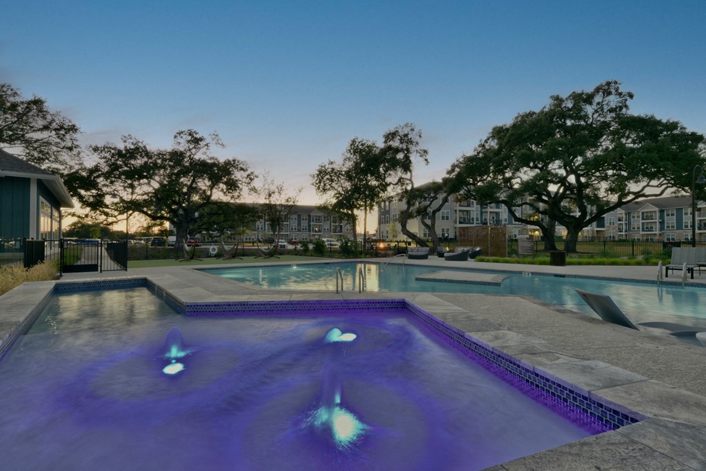 a swimming pool with purple lights on it at dusk
