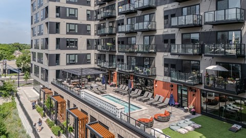 A modern apartment complex with a pool and lounge area.