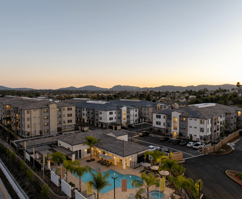 A large apartment complex with a pool and palm trees.