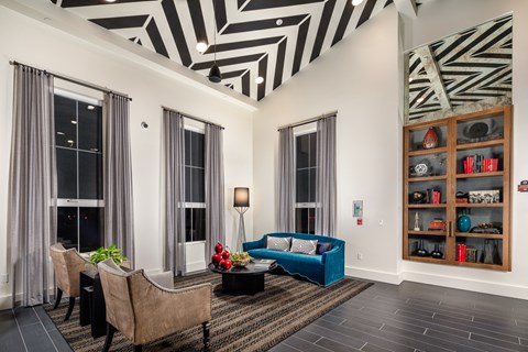 A living room with a blue couch and a black and white striped ceiling.
