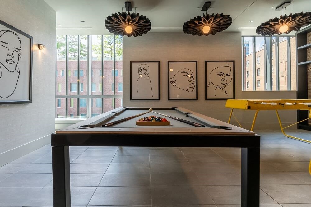 a pool table in a room with three paintings on the wall