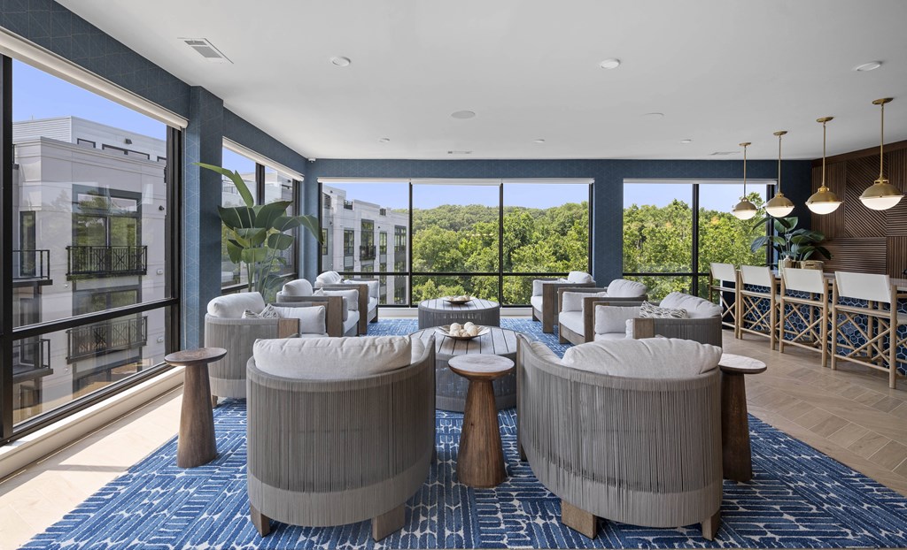 a lounge area with chairs and tables and large windows
