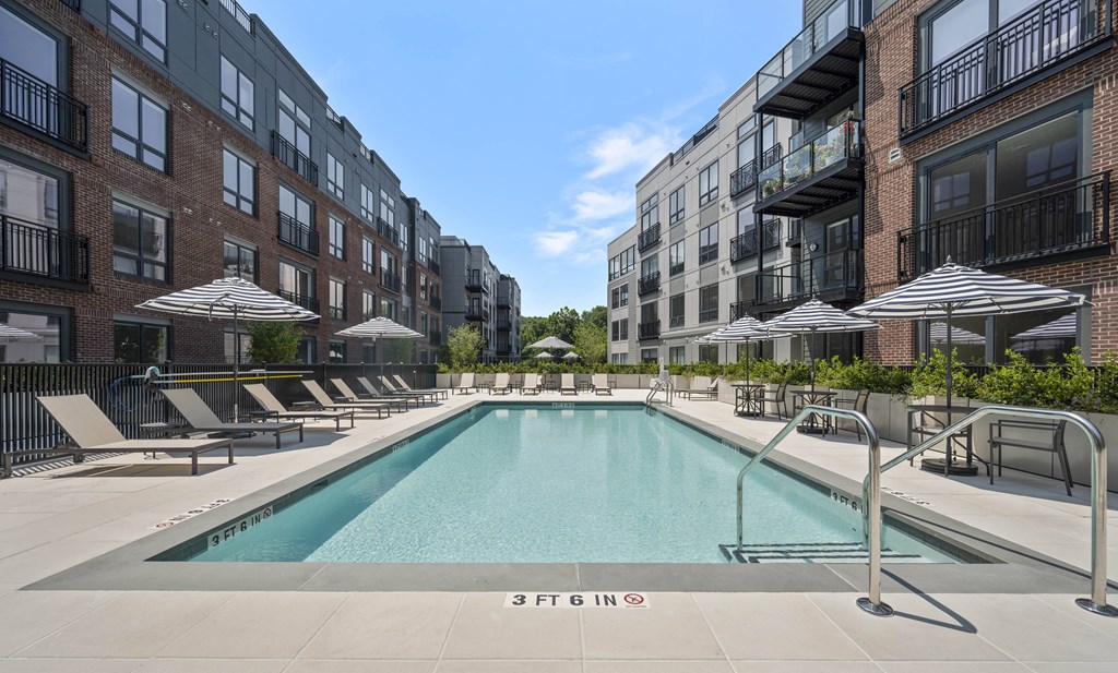 a swimming pool with umbrellas in front of an apartment building
