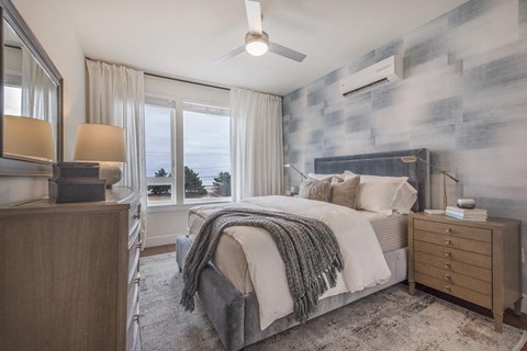 Furnished bedroom with ocean views, accent wall, ceiling fan and dresser