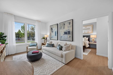 A living room with a couch, a chair, a table, and two paintings on the wall.