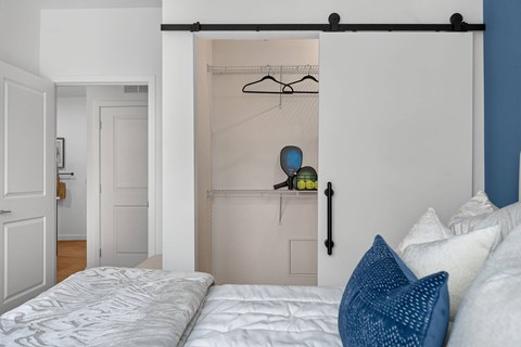 A bedroom with a bed and a closet with a hanging rod.