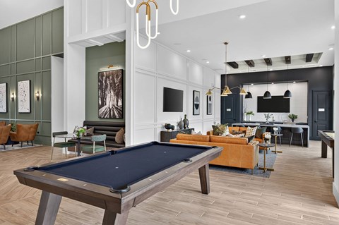 A pool table is in the middle of a room with a green wall and a TV.