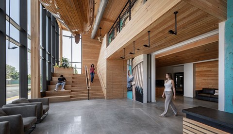 A woman is walking through a modern, wood-paneled lobby.