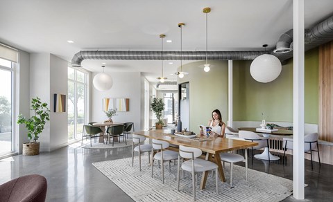 A woman is sitting at a table in a modern dining room.
