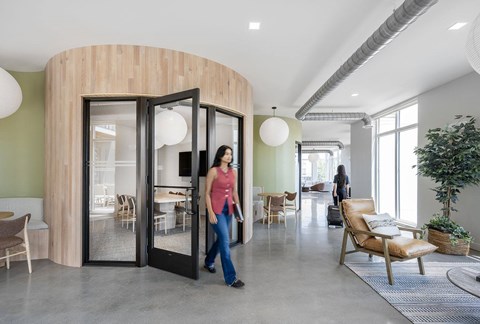 A woman is walking through a revolving door in a modern room.
