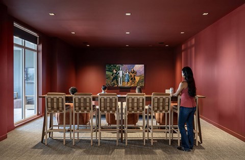 A woman stands in front of a large painting in a room with red walls.