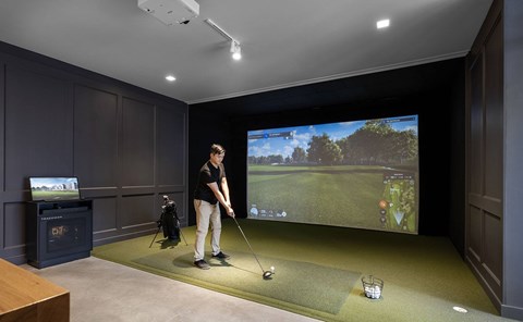 A man is playing a golf game on a big screen.