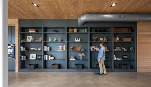 A man is standing in front of a shelf with various items on it.