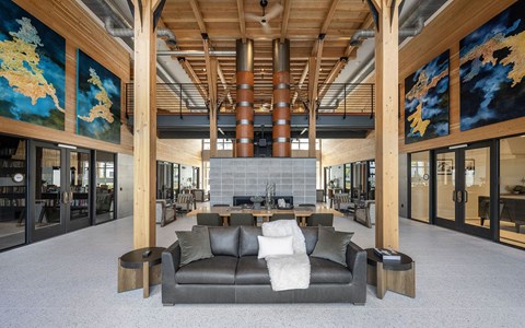 A living room with a grey couch and wooden pillars.