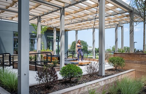 A woman is dancing on a wooden platform under a pergola.