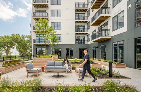 A man and a woman are walking on a patio in front of a modern building.