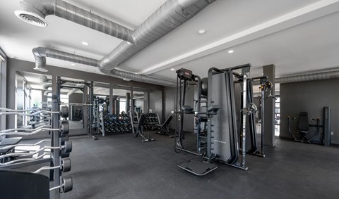 A spacious gym with various exercise equipment and a ceiling fan.