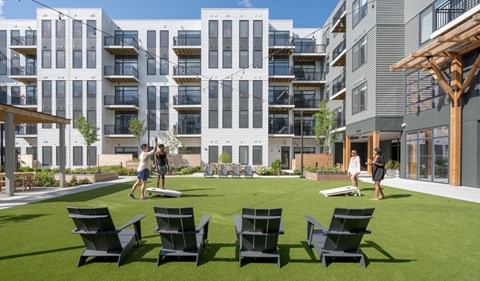 A group of people are standing on a lawn in front of apartment buildings.