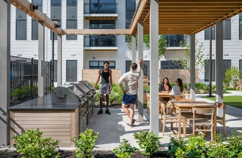 A man in a white shirt and blue shorts is standing on a patio with a woman in a black tank top and shorts.