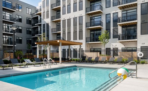 A swimming pool in front of a modern apartment building.