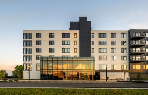 A modern building with a glass facade is illuminated by the setting sun.