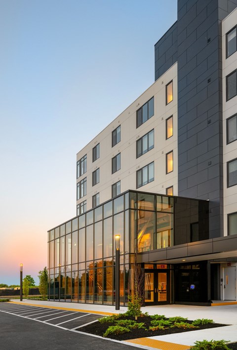 A modern building with a glass facade and a parking lot in front.