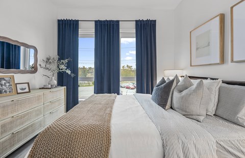 A bedroom with a large bed and a dresser with a mirror.