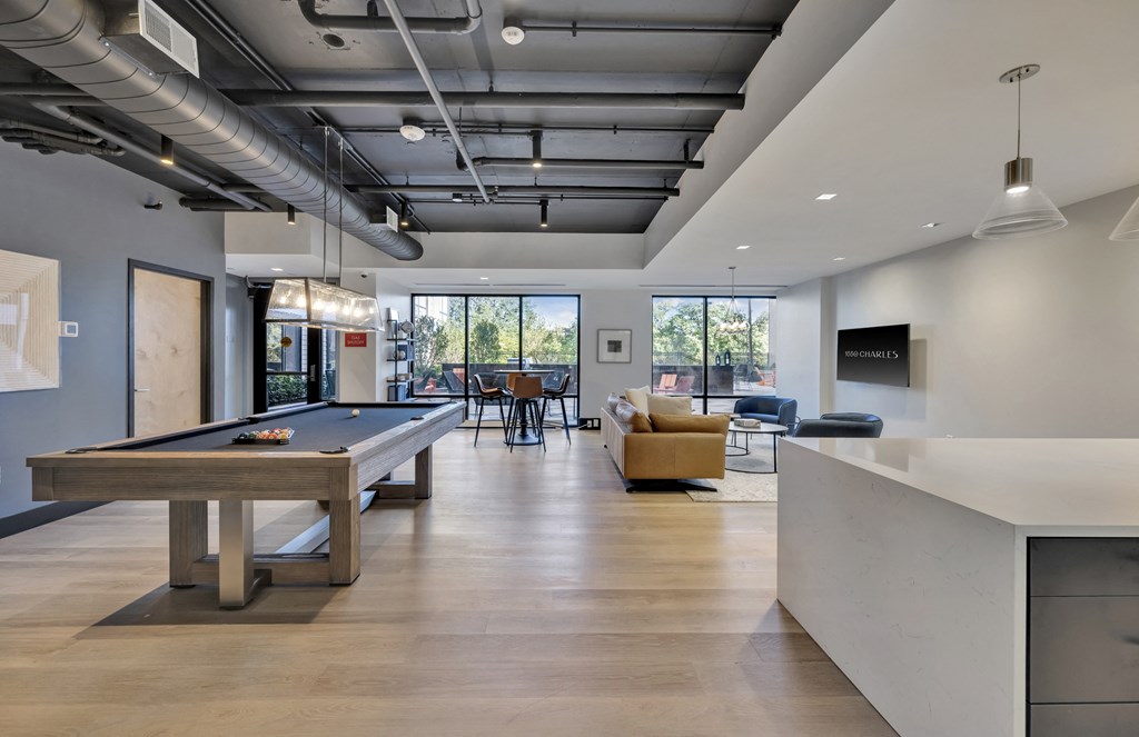 Community lounge area with plush seating, billiards table, board games, and entertainment kitchen